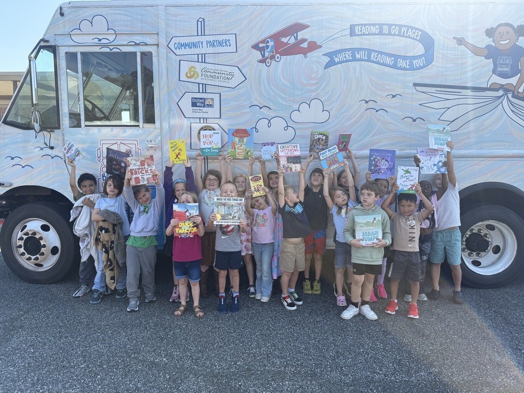 group of students holding up their books in front of the book mobile
