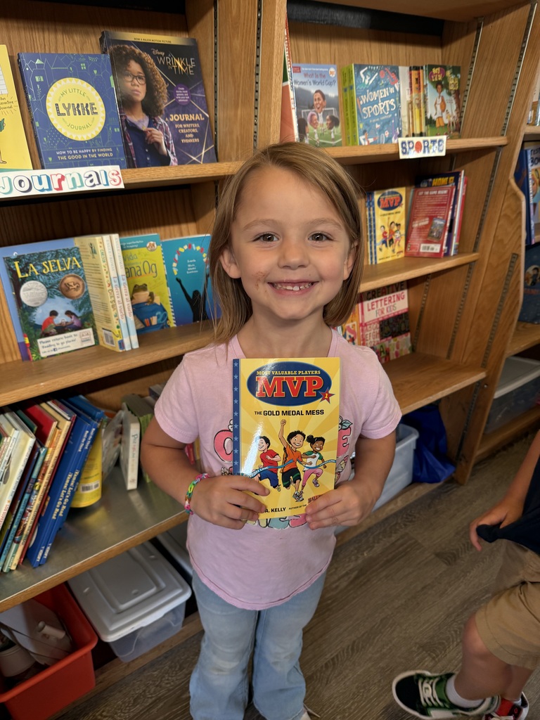 student holding up a book in the book mobile