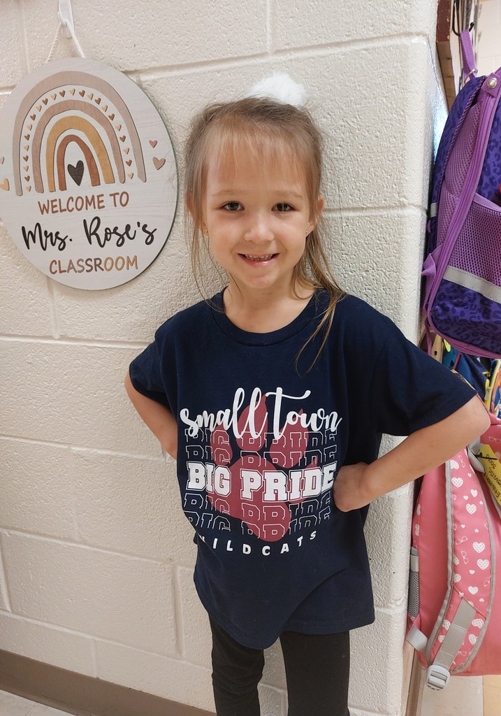 a girl standing in the hall with a shirt on that says "small town big pride wildcat"