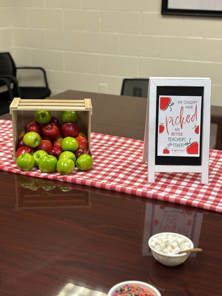 table with crates of apples, red checkered table cloth, a variety of toppings! 