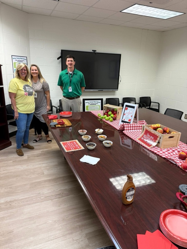table with crates of apples, red checkered table cloth, a variety of toppings! 