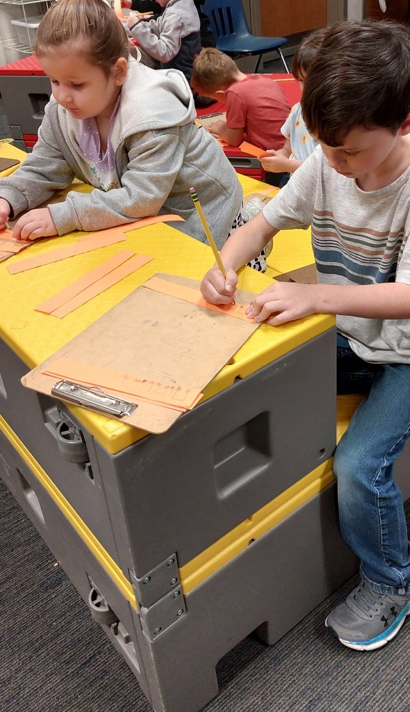 There is a girl and a boy drawing strips for pumpkins. 