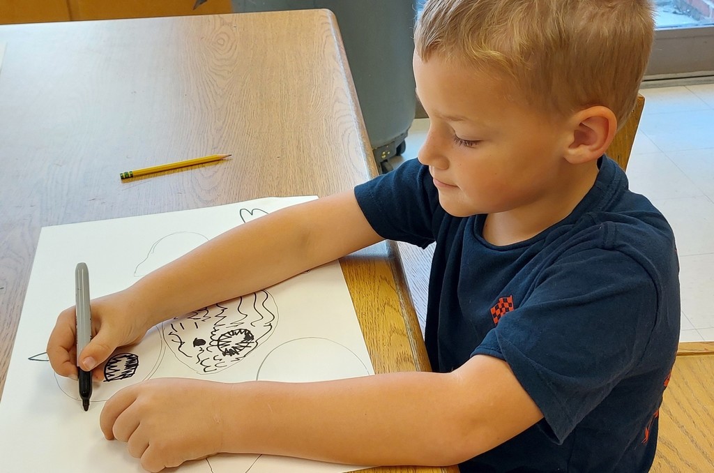 A boy is drawing fish using a black marker.
