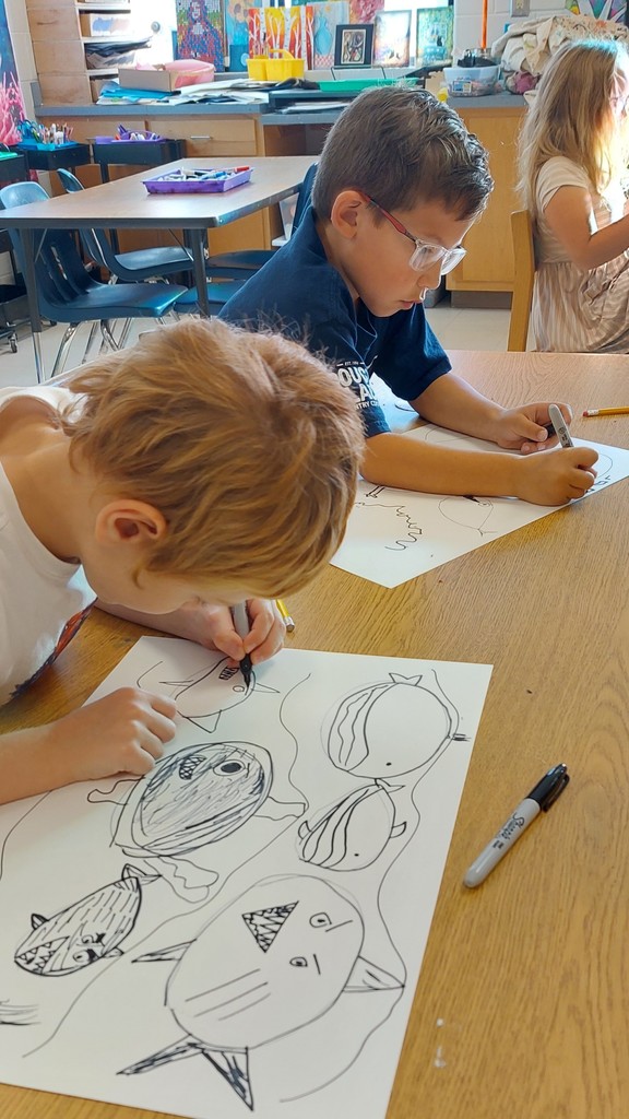 Two boys are drawing fish using markers.
