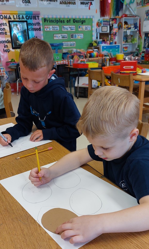 Two boys are drawing fish using a pencil