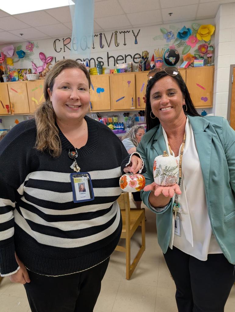 two teachers holding up their decorated pumpkins