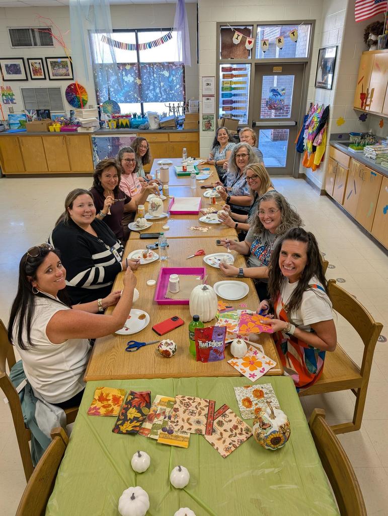A group of teaches sitting at a table decorating pumpkins