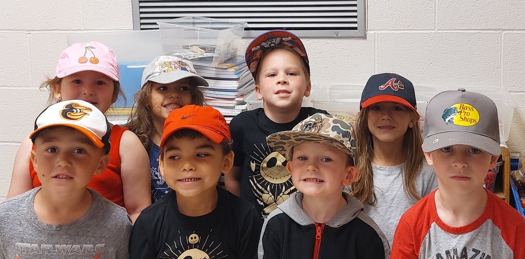 five boys and three girls are in the picture all wearing various hats