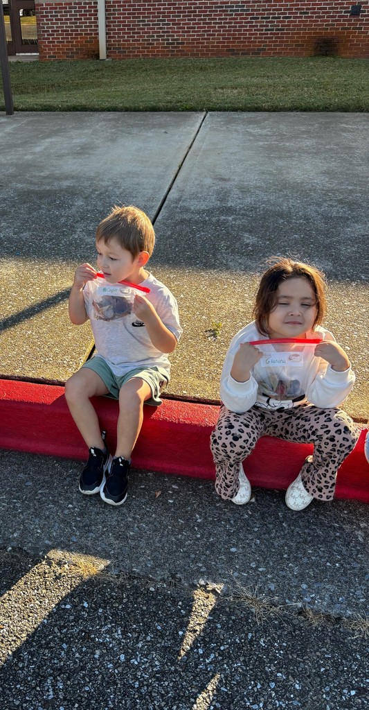 students holding up bags of items they found on the ground outside