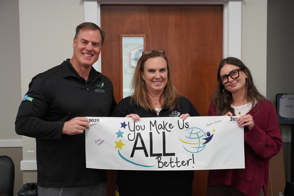 Superintendent Terza, Natalie Adams, and Anna Clark posing for a picture with a banner.