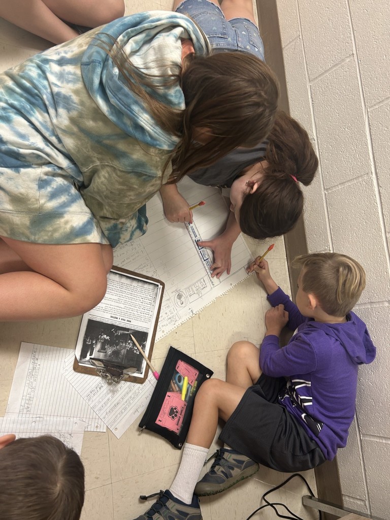 three students on floor writing on paper