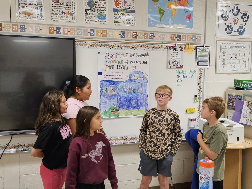 three boys and three girls standing in front of the board with their project on chart paper