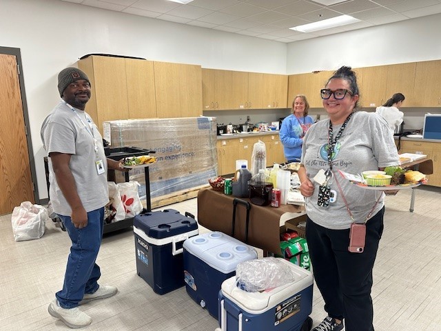 Teachers smiling for a picture as they get food for our Thanksgiving lunch.