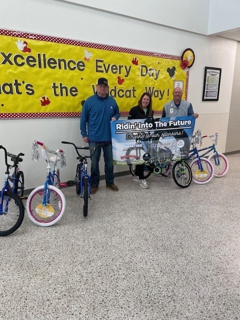 Mrs. Stephens and sponsors smiling for a picture with bikes that have been donated. 