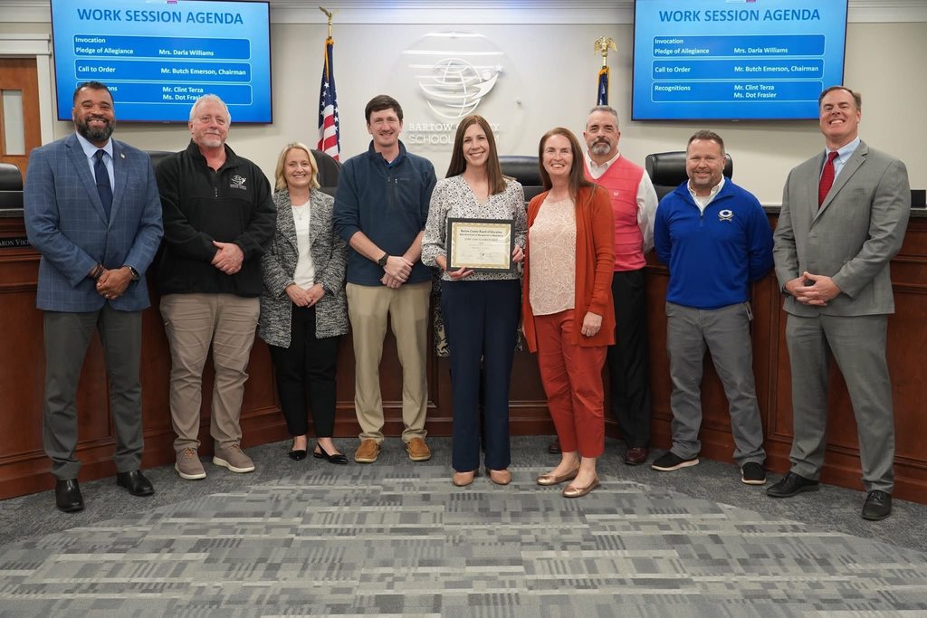 9 people standing and holding an award. 3 women and 6 men.