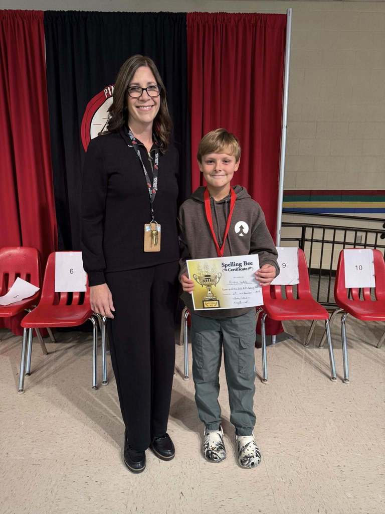A woman and boy standing in front of red chairs holding a certificate 