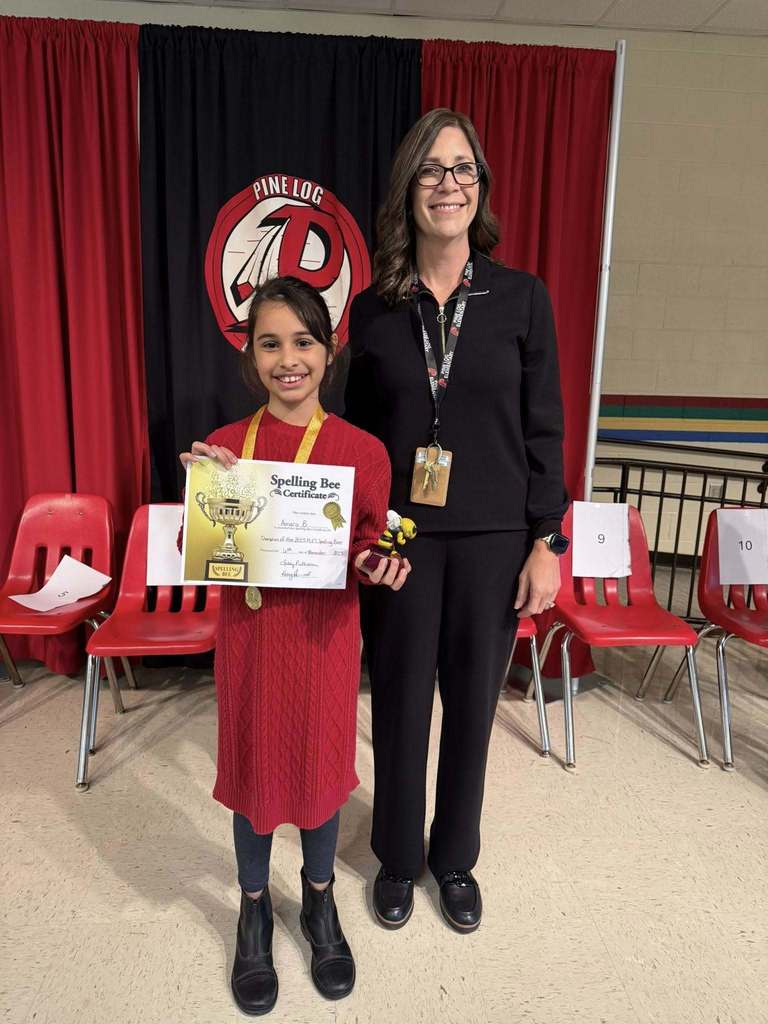 A woman and girl standing in front of red chairs holding a certificate 