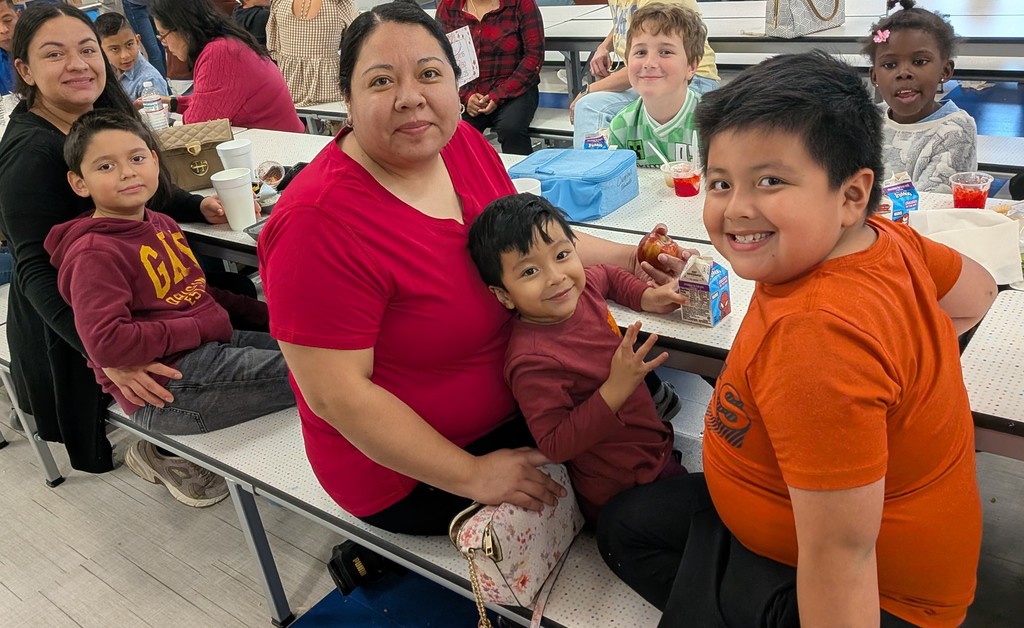 Families smiling and eating thanksgiving lunch.