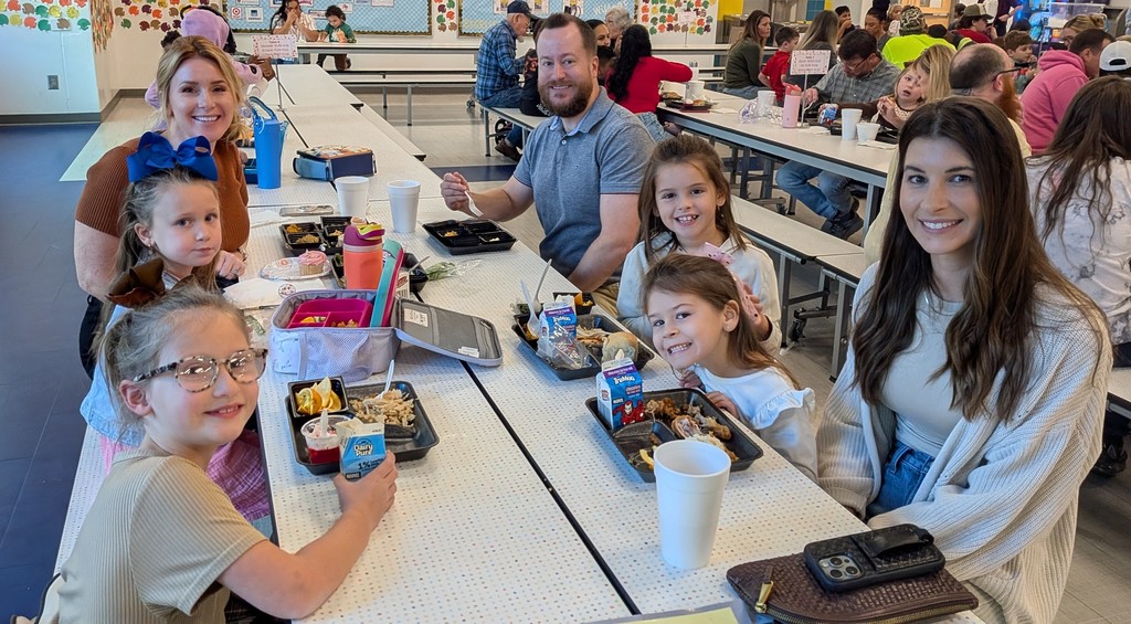 Families smiling and eating thanksgiving lunch.