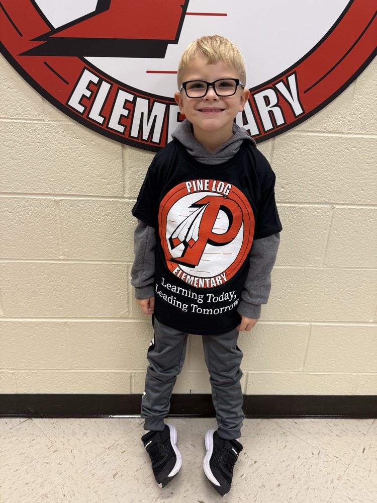 a boy wearing a black shirt with a P, pine log logo on it