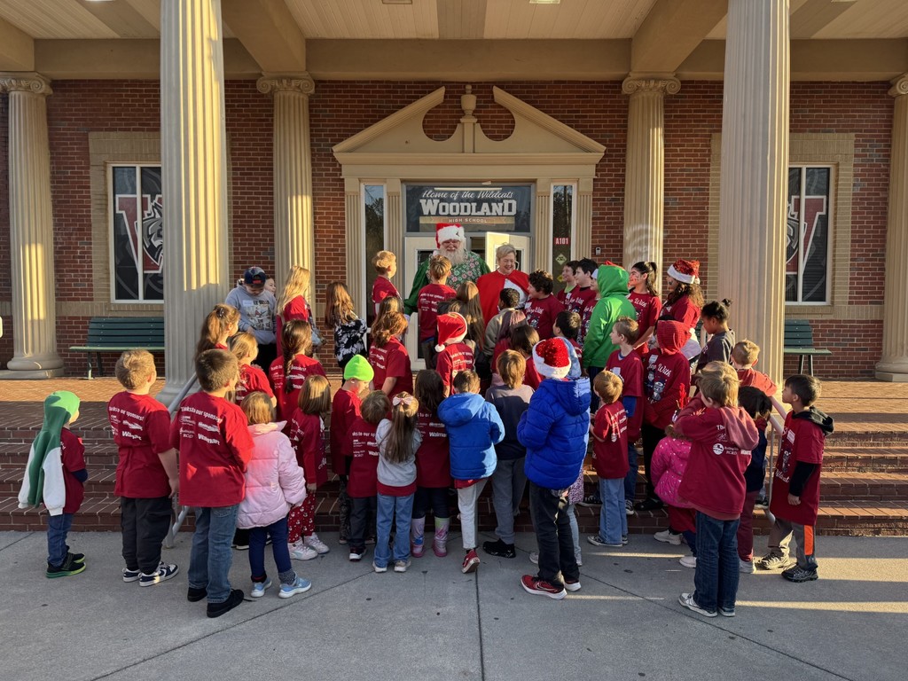 Students with Santa and Mrs. Claus on steps of school building