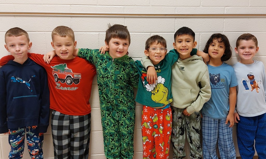 seven boys standing in a line with their arms around each other - all wearing pajamas