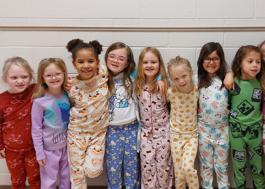eight girls standing in a line with their arms around each other - all wearing pajamas