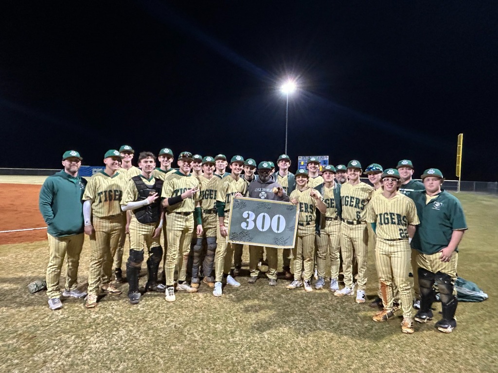 A group of people in baseball uniforms pose for a photo, holding a sign with the number 300.