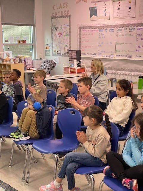 A board member watching a first grade class present their writing. 