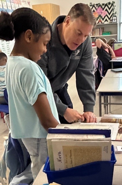 Mr. Terza talking to a fourth grade student about her writing. 