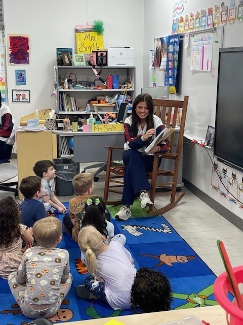 High school cheerleader reading to a PreK class.