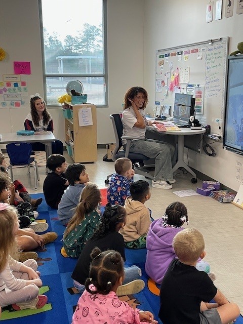High school cheerleader reading to a kindergarten class.