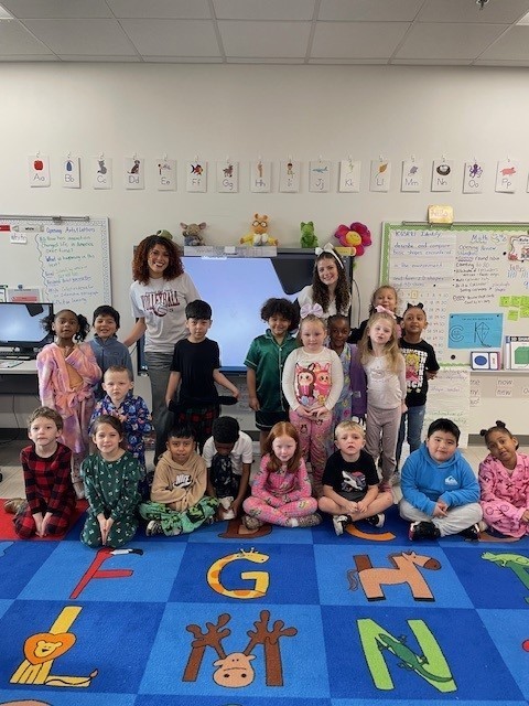 High school cheerleaders and a kindergarten class smiling for a picture.