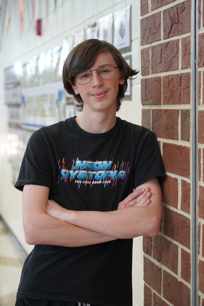 Person in glasses and a black t-shirt with the words "Neon Dystopia" stands in a hallway.