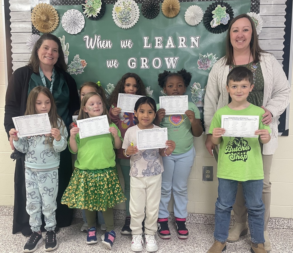 Principal Mrs. LaRue and Assistant Principal Dr. Payne stand with a group of seven first grade students who are holding positive office referrals. 