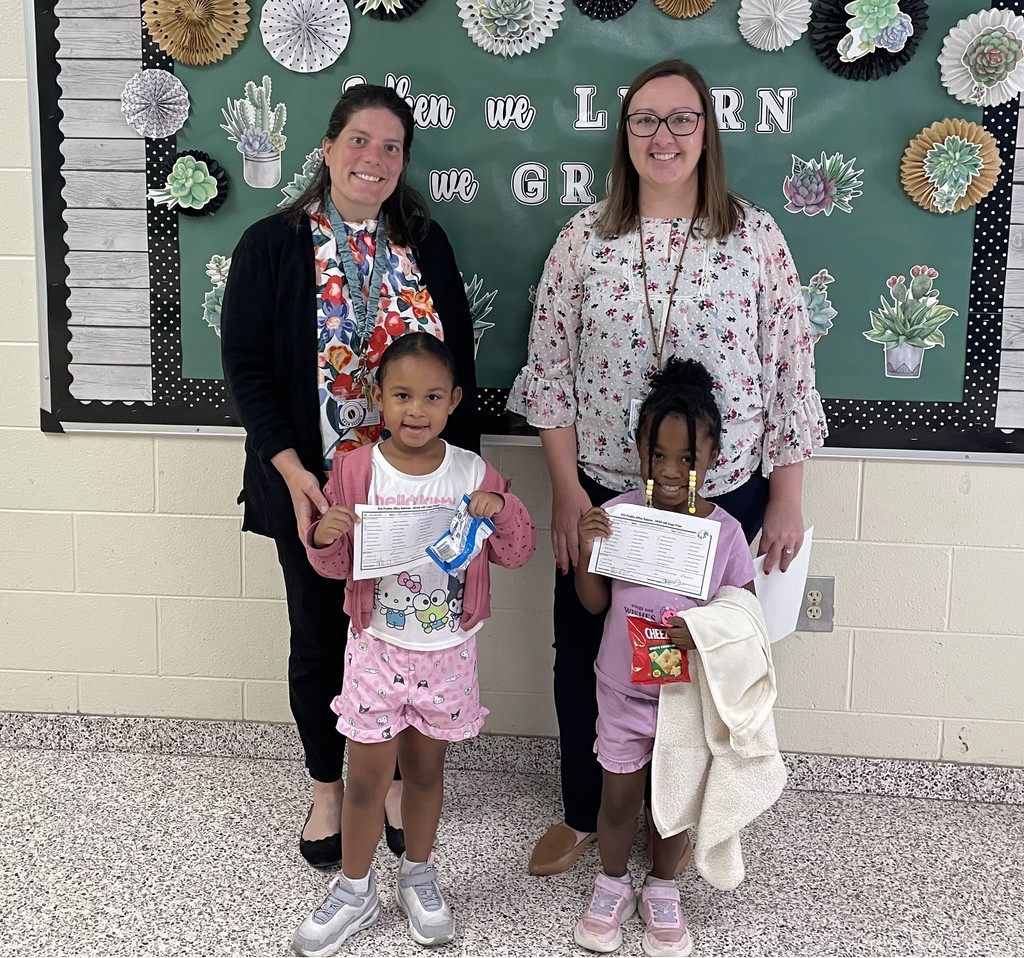Principal Mrs. LaRue and Assistant Principal Dr. Payne stand with two girls who are holding certificates.  
