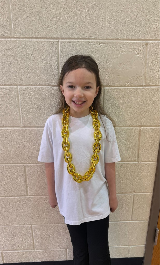 A young girl in a white T-shirt with a yellow chain around her neck. She is smiling.
