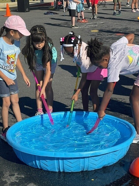 Second grade girls playing a water game during field day.