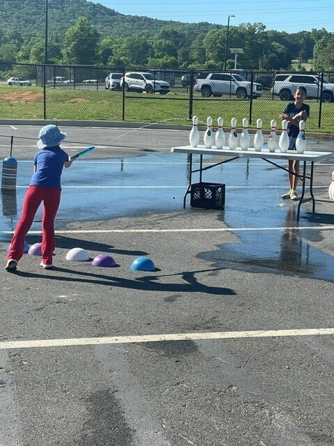 Student using a water toy to knock down bowling pins. 