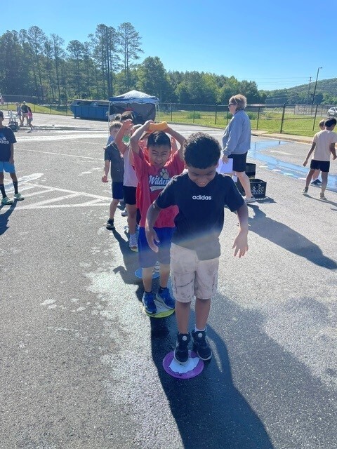 Students playing a field day event with a wet sponge on their head. 