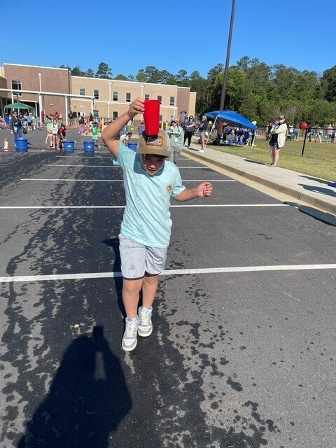 A student walking with a bucket of water for a field day event.