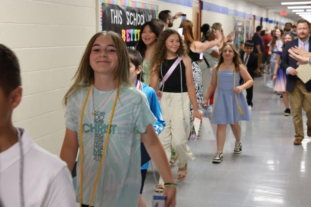 School hallway with students in casual clothing walking past a banner that reads "This School is ICTT".