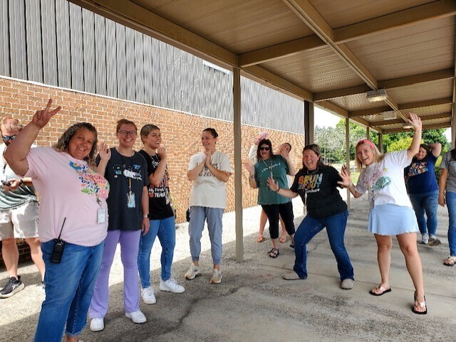 A group of people, wearing casual clothes, are posing for a photo in an outdoor area.