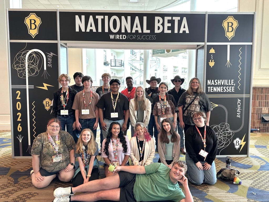 Group of young people in a conference room pose for a picture in front of a National Beta banner.