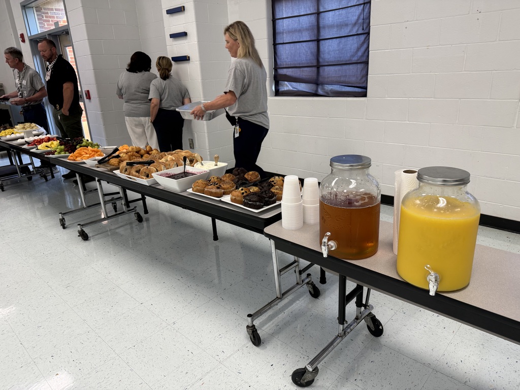 A buffet table with various foods and drinks, including juice, in a room with people.