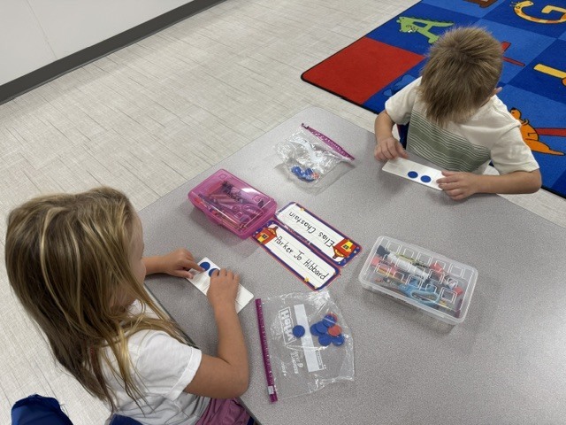 Two students using chips to show a number on a ten frame.