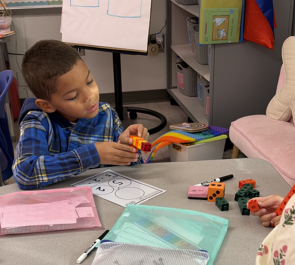 A first grade student using blocks to add two numbers.