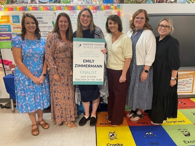 Ms. Zimmerman smiling for a picture with her administration and academic coaches.