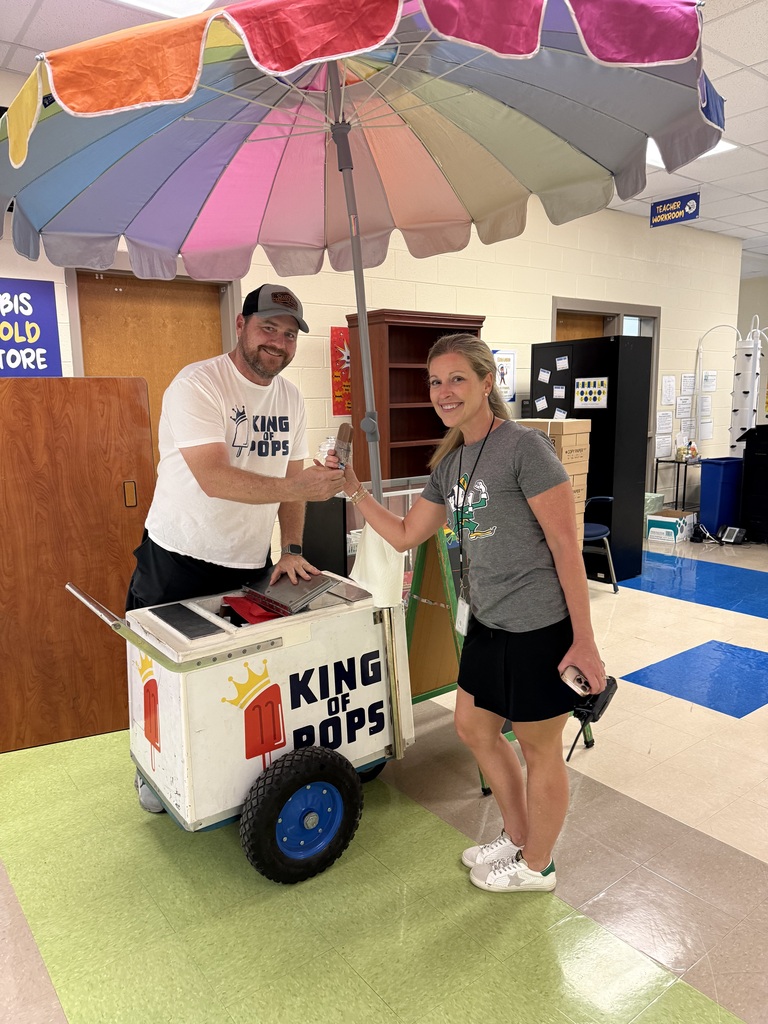 Two people are standing in a room next to a cart with the words "King Pops" on it.