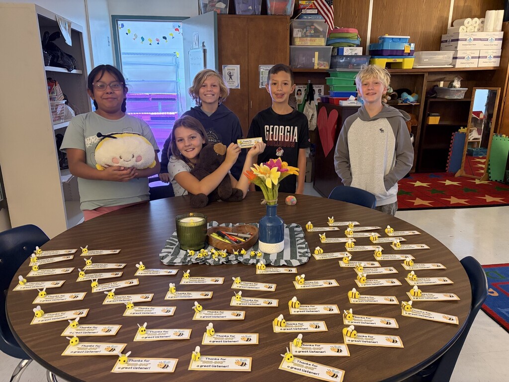 Six children stand around a table displaying a pumpkin, a vase with flowers, and numerous cards.